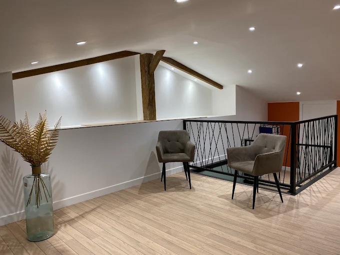 Mezzanine sous combles : murs et plafonds blancs, poutres apparentes, parquet clair