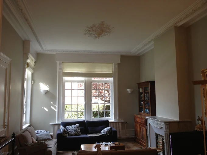 Salon aux moulures anciennes repeint en gris clair